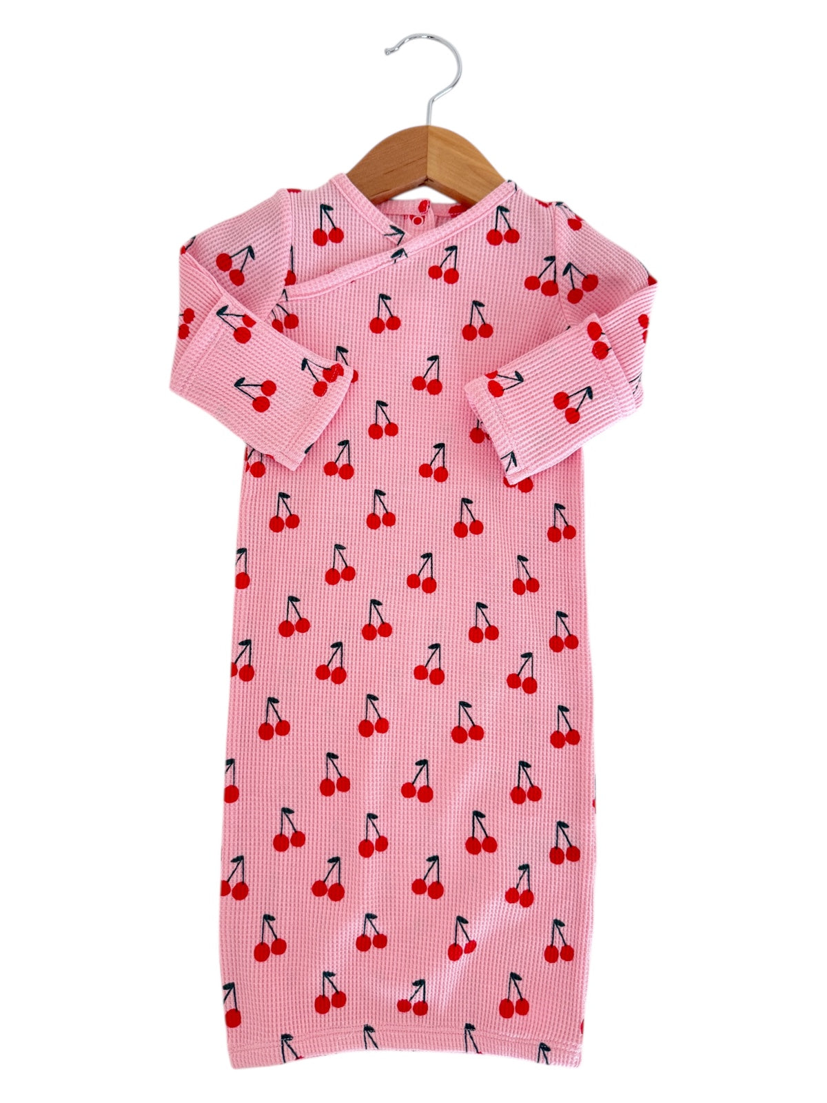 Pink children's dress with cherry print, featuring long sleeves and a hanging loop. Suitable for casual wear.