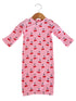 Pink dress with red cherry print, hanging on a wooden hanger.