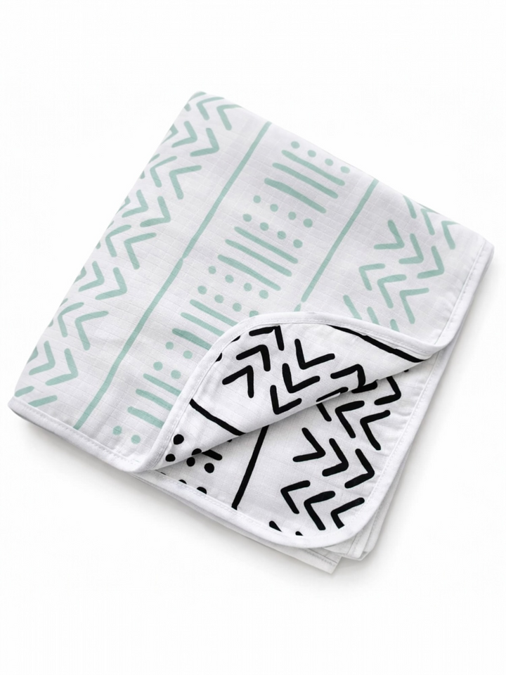 A folded blanket featuring a modern geometric pattern in mint green and black on a white background.
