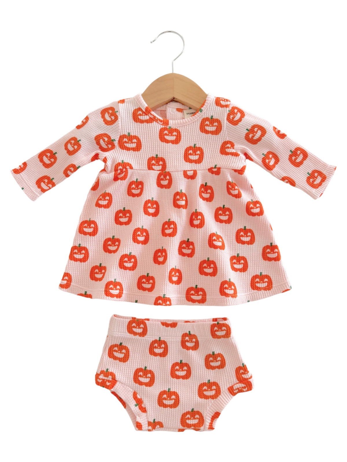 Pink children's outfit with pumpkin pattern, featuring a long-sleeve dress and matching shorts.