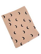 Neutral-toned fabric with black crescent moon patterns, folded neatly. Ideal for aesthetic decor or fashion.