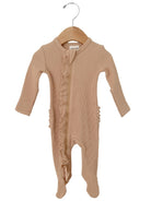 Light beige baby onesie with ruffle detailing, featuring long sleeves and footed legs, displayed on a wooden hanger.
