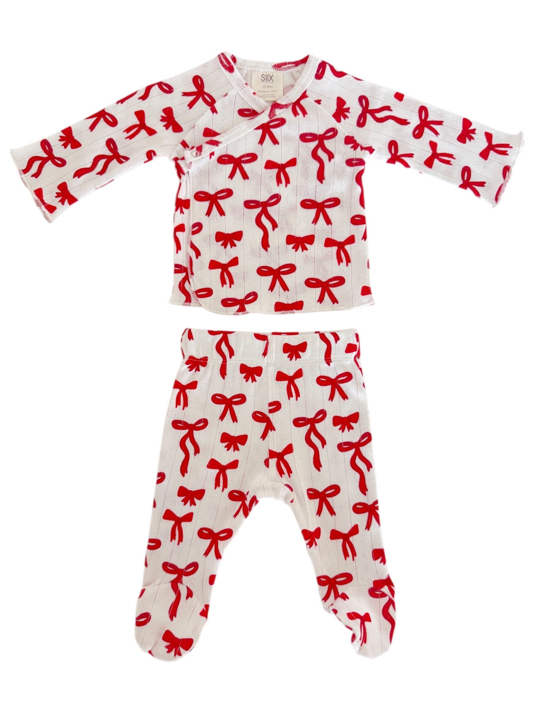 Red bow-patterned baby pajama set featuring a long-sleeve top and matching pants on a white background.