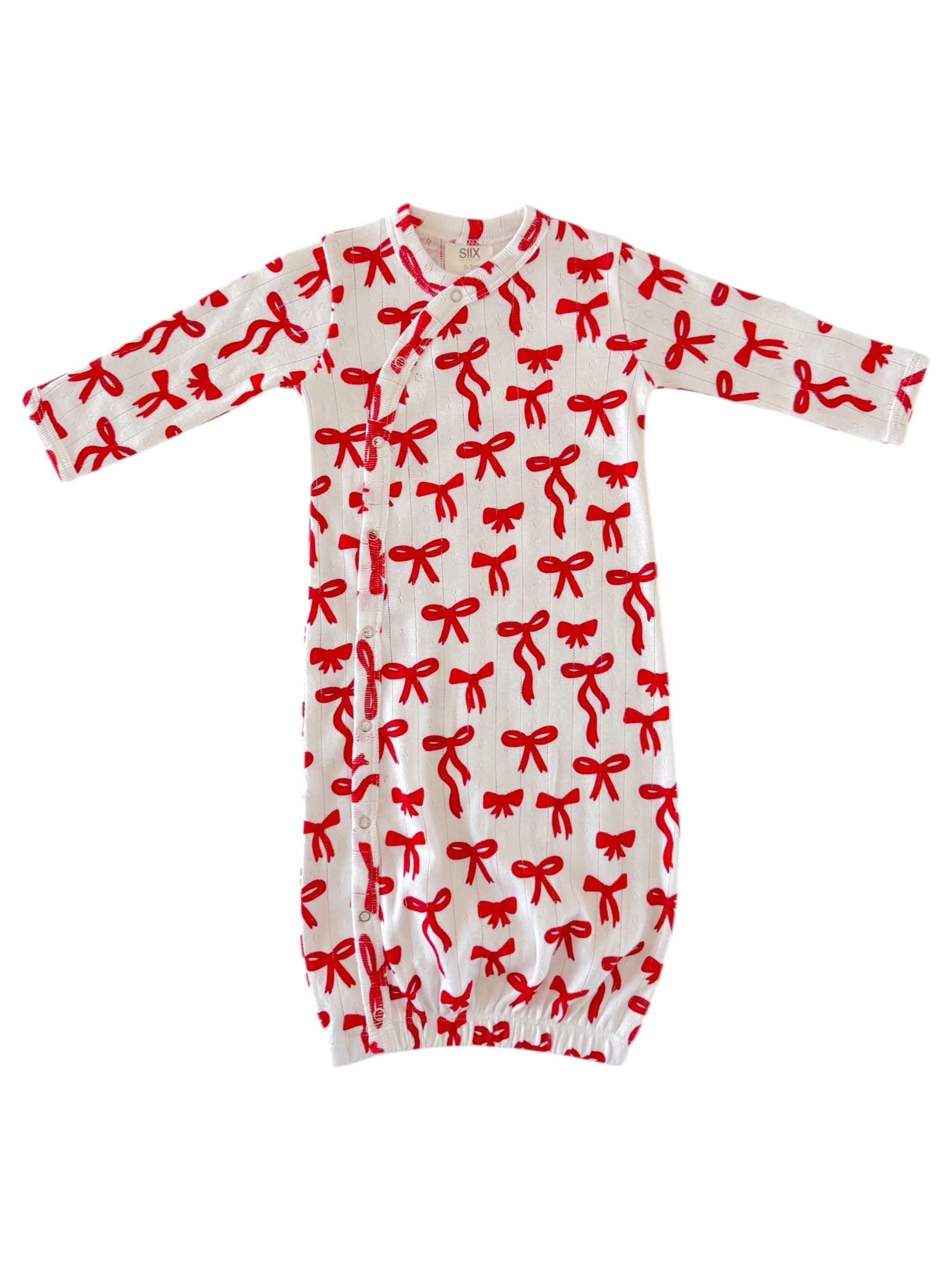 White baby gown with red bow print, featuring long sleeves and snap closures at the front.