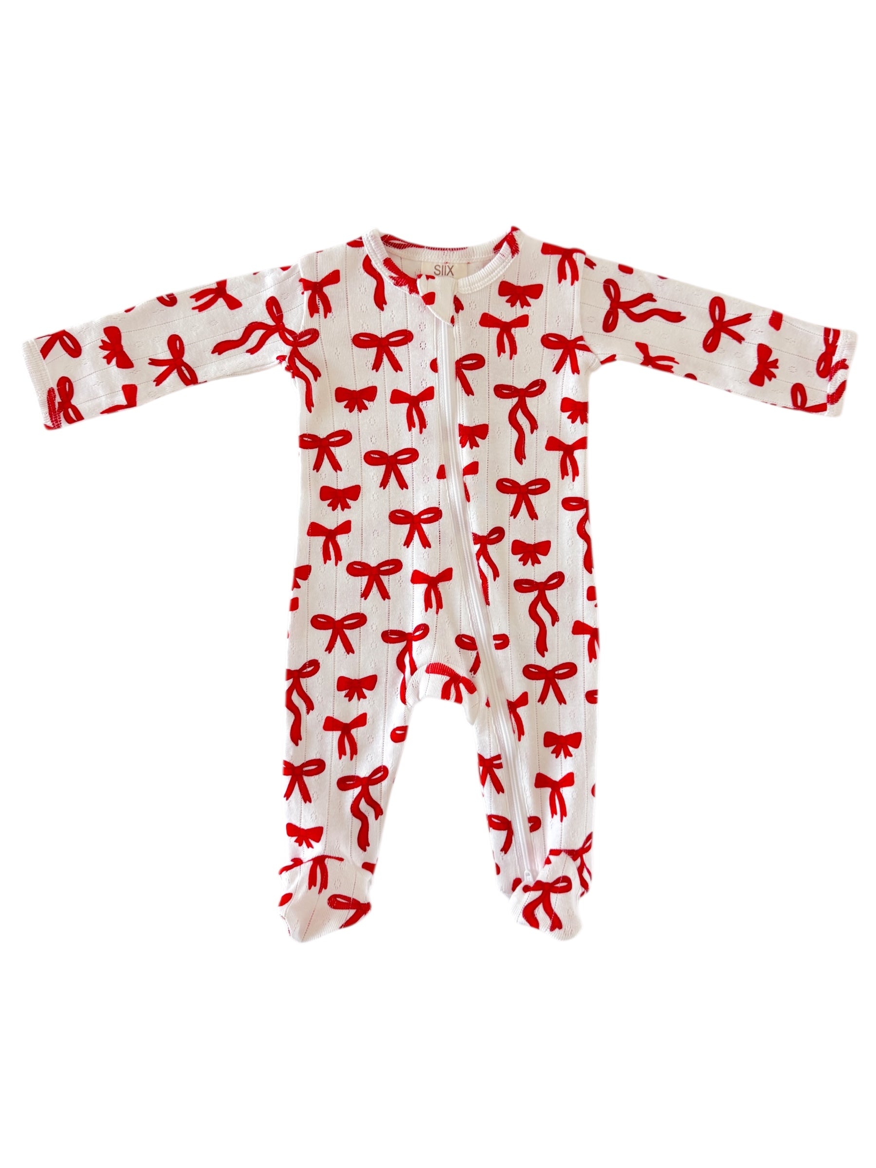 White baby onesie with red bow pattern and long sleeves, featuring a front zipper closure.