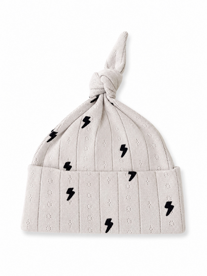 Knot-structured light gray baby hat with black lightning bolt patterns. Ideal for stylish infant wear.