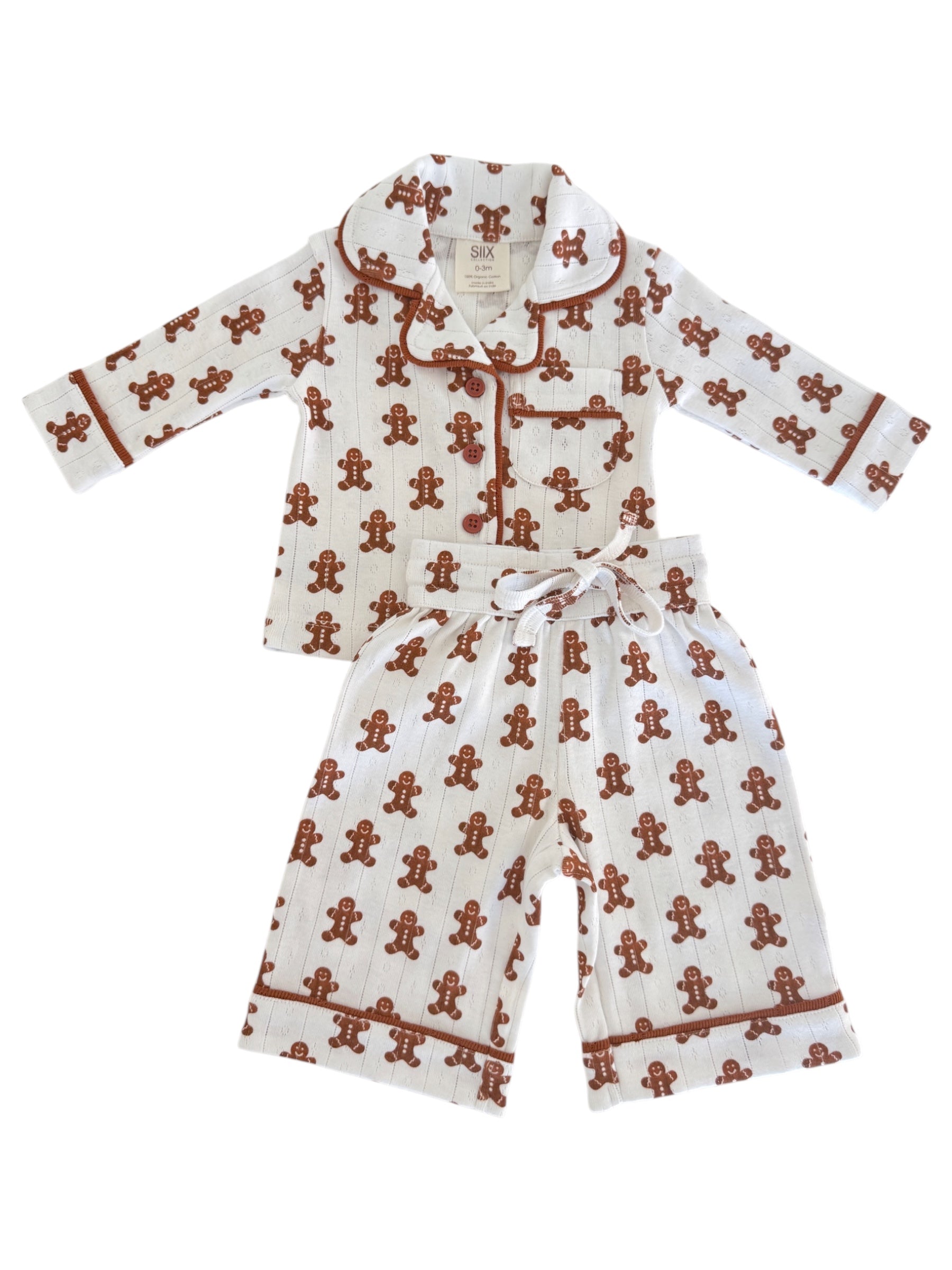 White pajama set with gingerbread man pattern, featuring long sleeves and pants, ideal for cozy nights.