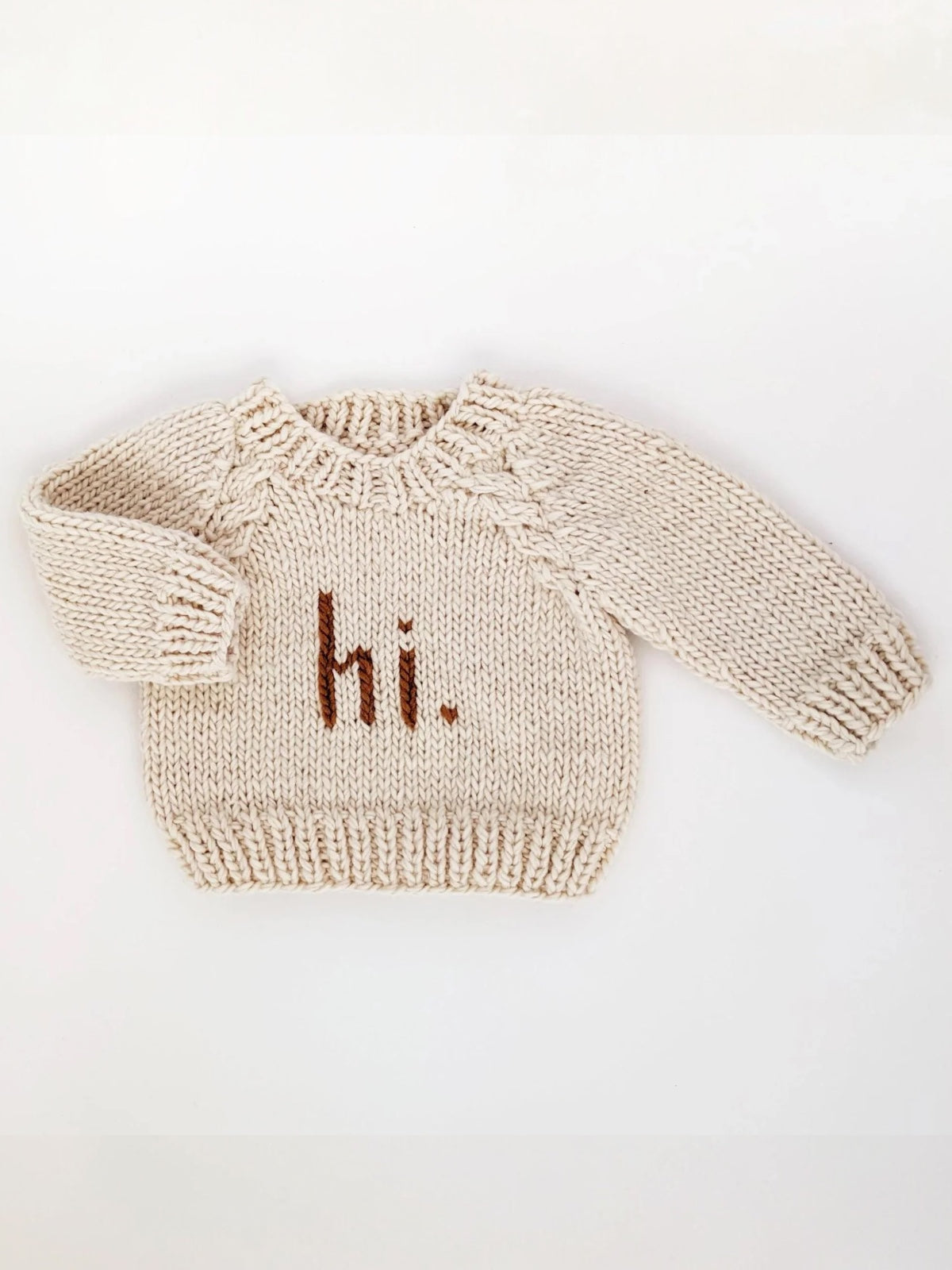Cream-colored knit sweater with "hi." text displayed prominently on the front.