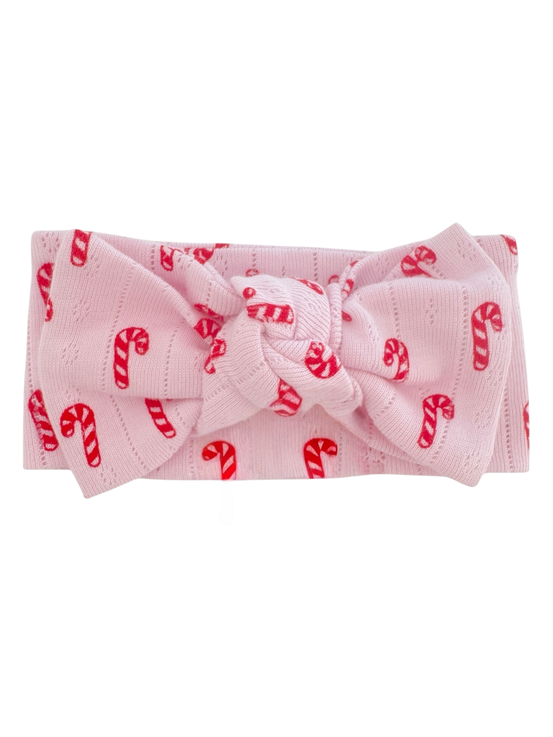 Pink headband with a large bow, decorated with red candy cane patterns. Ideal for festive occasions.