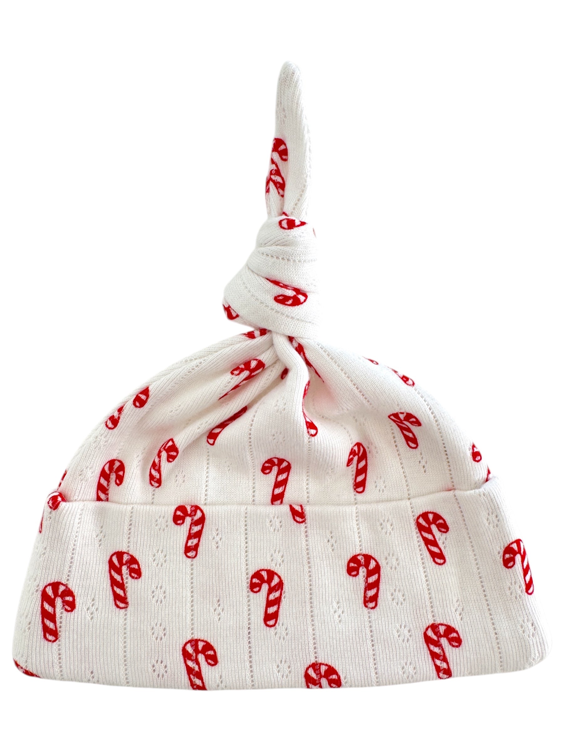 White baby hat with red candy cane pattern and a playful knot at the top.