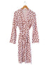 Pink robe with gingerbread man print, featuring long sleeves and a tie belt, hanging on a wooden hanger.