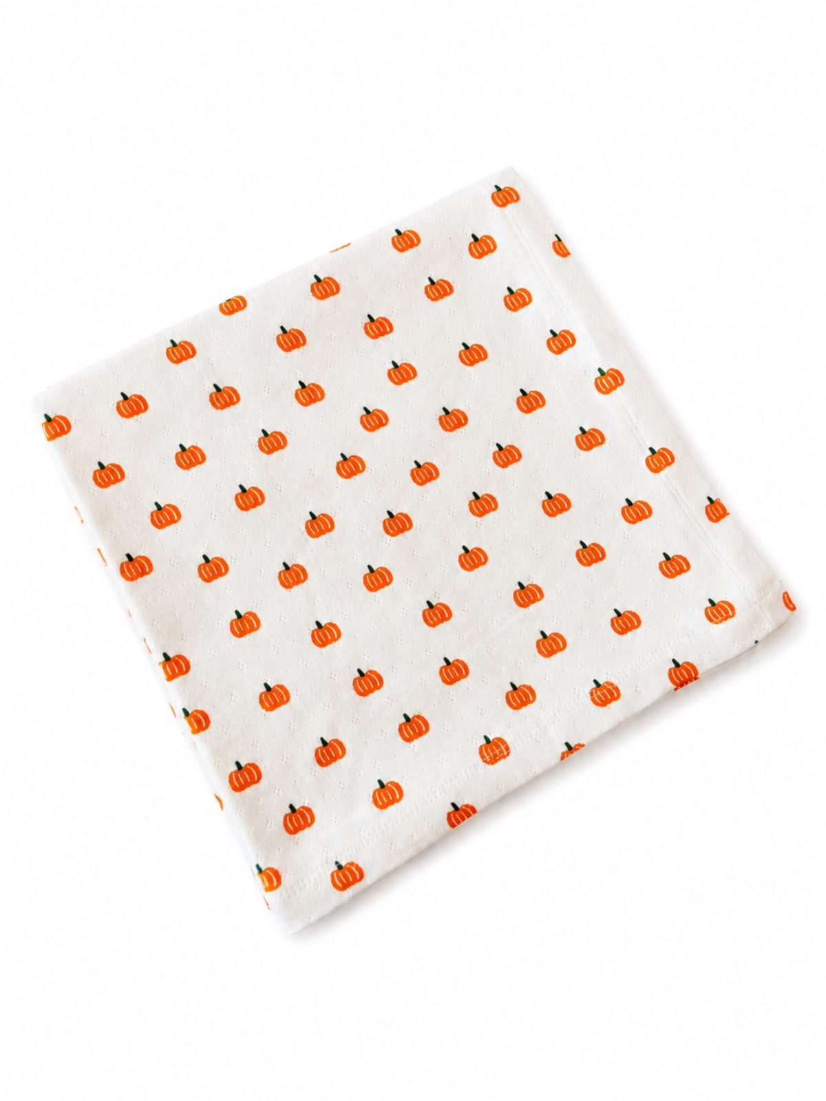 White fabric featuring a repeating pattern of small orange pumpkins.