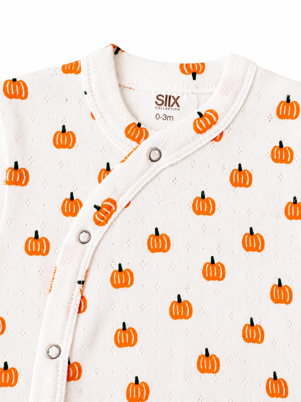 White onesie for infants, featuring a pumpkin print in orange and green, with a snap closure at the neck.