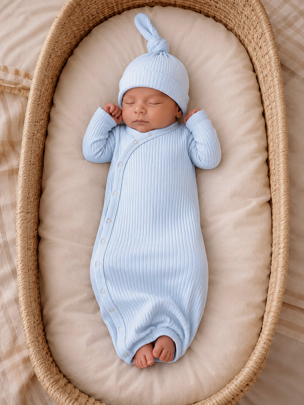 Newborn baby sleeping peacefully in a light blue ribbed outfit and hat, nestled in a cozy basket.