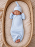 Newborn baby sleeping peacefully in a light blue ribbed outfit and hat, nestled in a cozy basket.