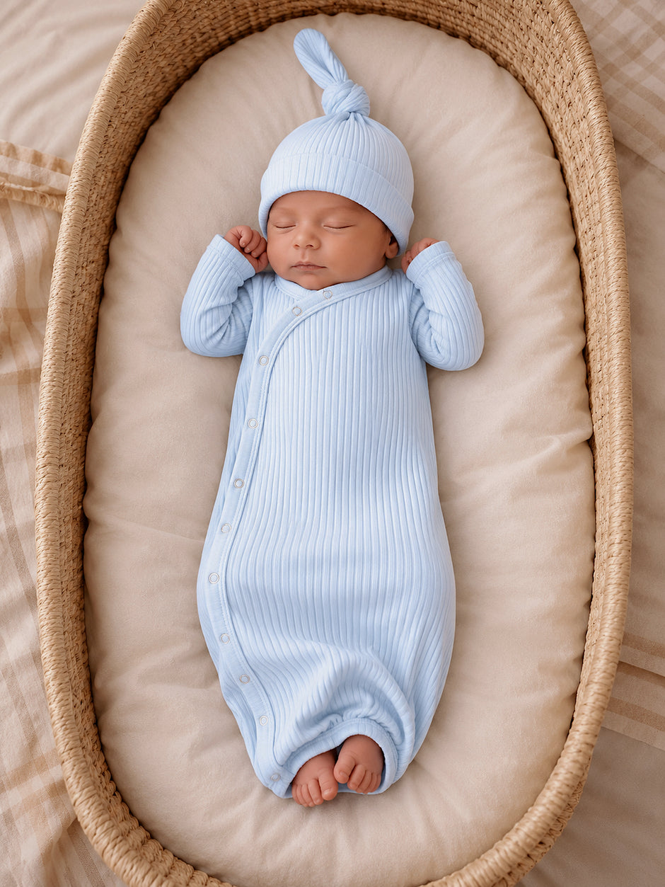 Newborn baby sleeping peacefully in a light blue ribbed outfit and hat, nestled in a cozy basket.