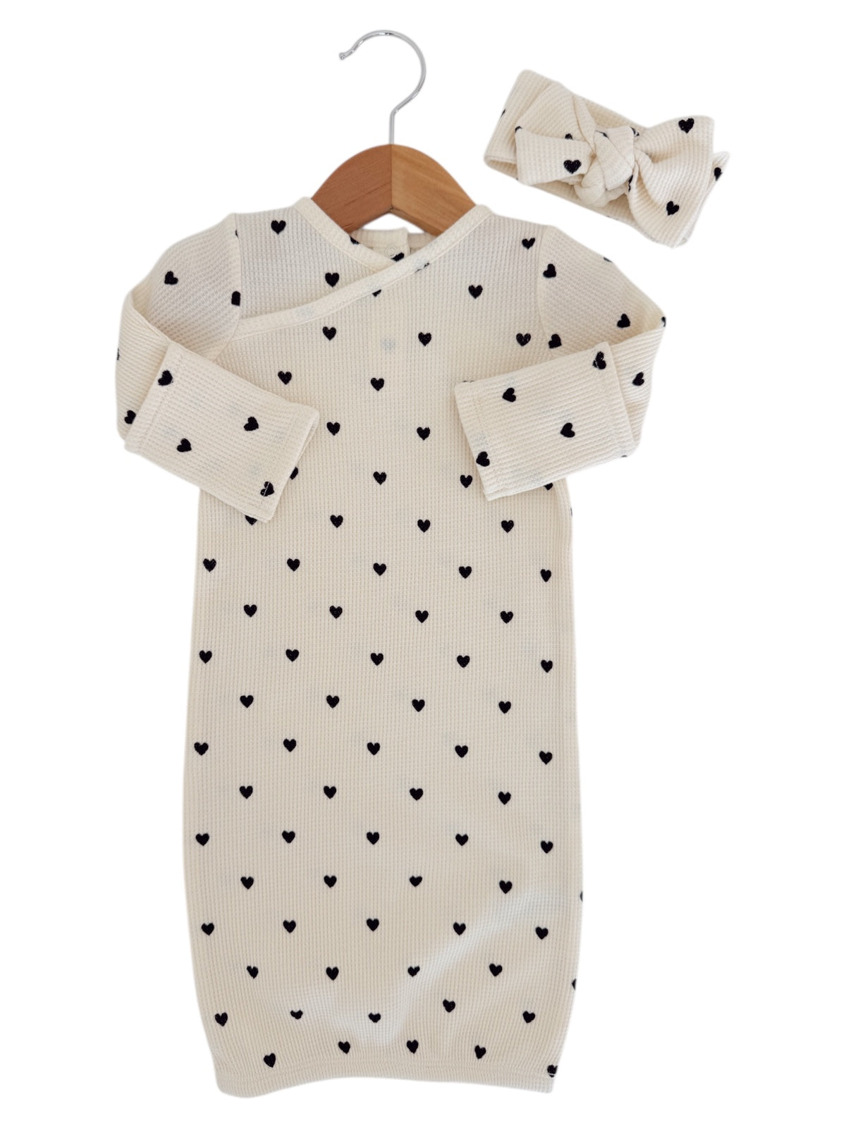 Infant ribbed dress with black heart pattern and matching headband, hanging on a wooden hanger.