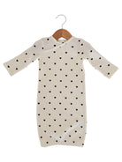 Cream dress with long sleeves and black heart patterns, hanging on a wooden hanger.