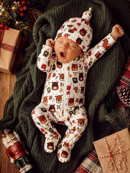Adorable baby yawning in festive animal print pajamas on a cozy blanket, surrounded by holiday decorations.