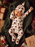 Adorable baby yawning in festive animal print pajamas on a cozy blanket, surrounded by holiday decorations.