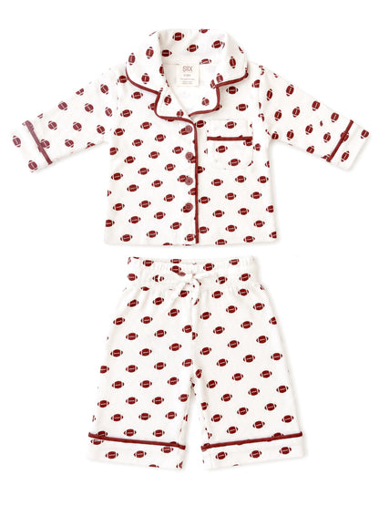 Kids' white pajama set with football print, featuring a button-up top and elastic waist shorts.