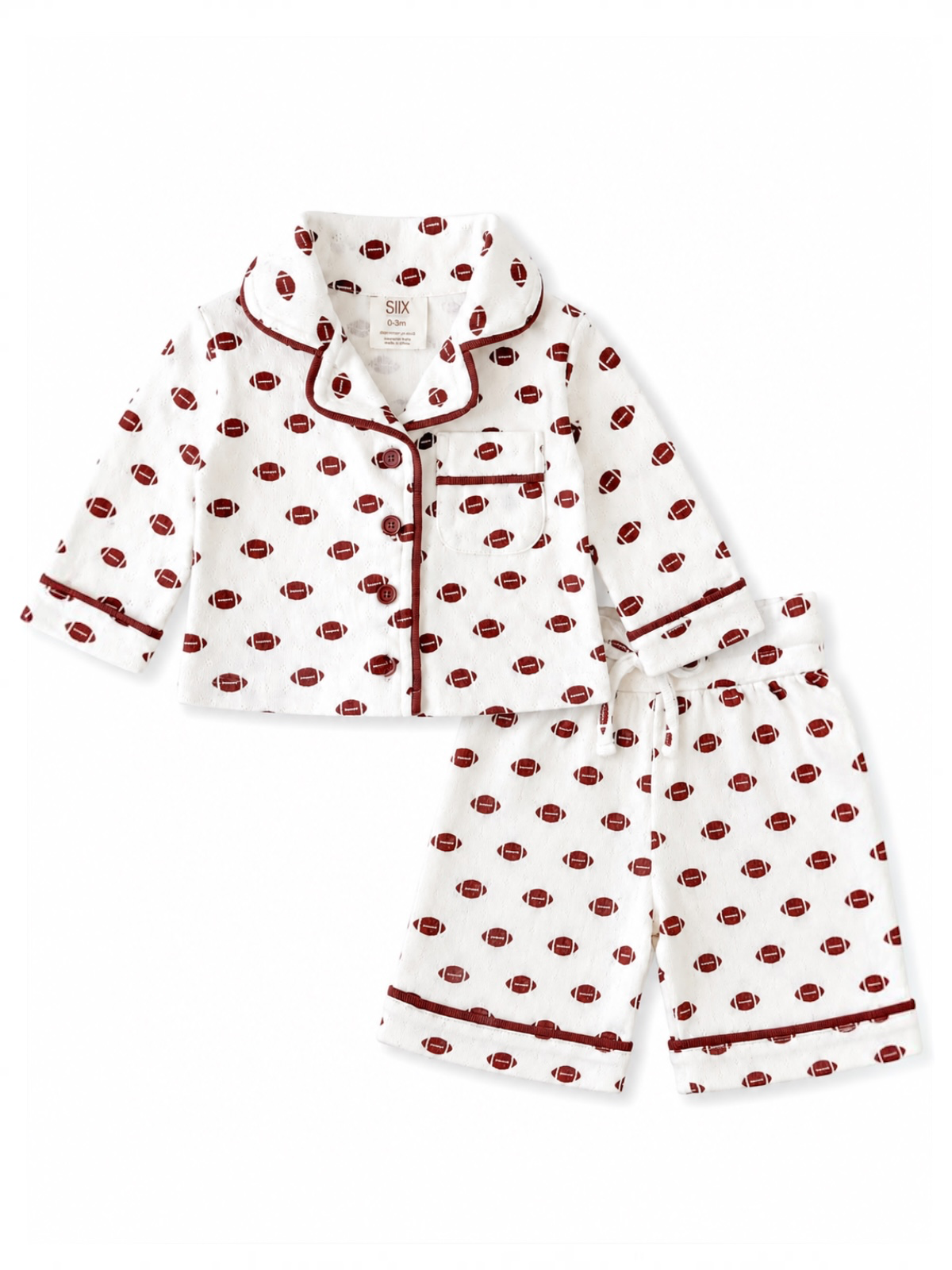 White children's pajamas featuring a football print in red, with a button-up top and shorts.