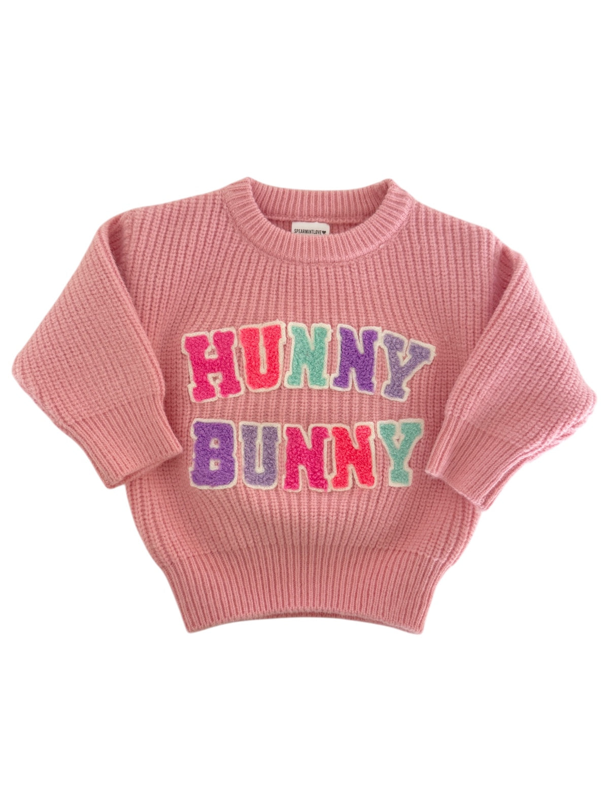 Pink sweater with "HUNNY BUNNY" in colorful letters on the front, featuring a ribbed design and short sleeves.