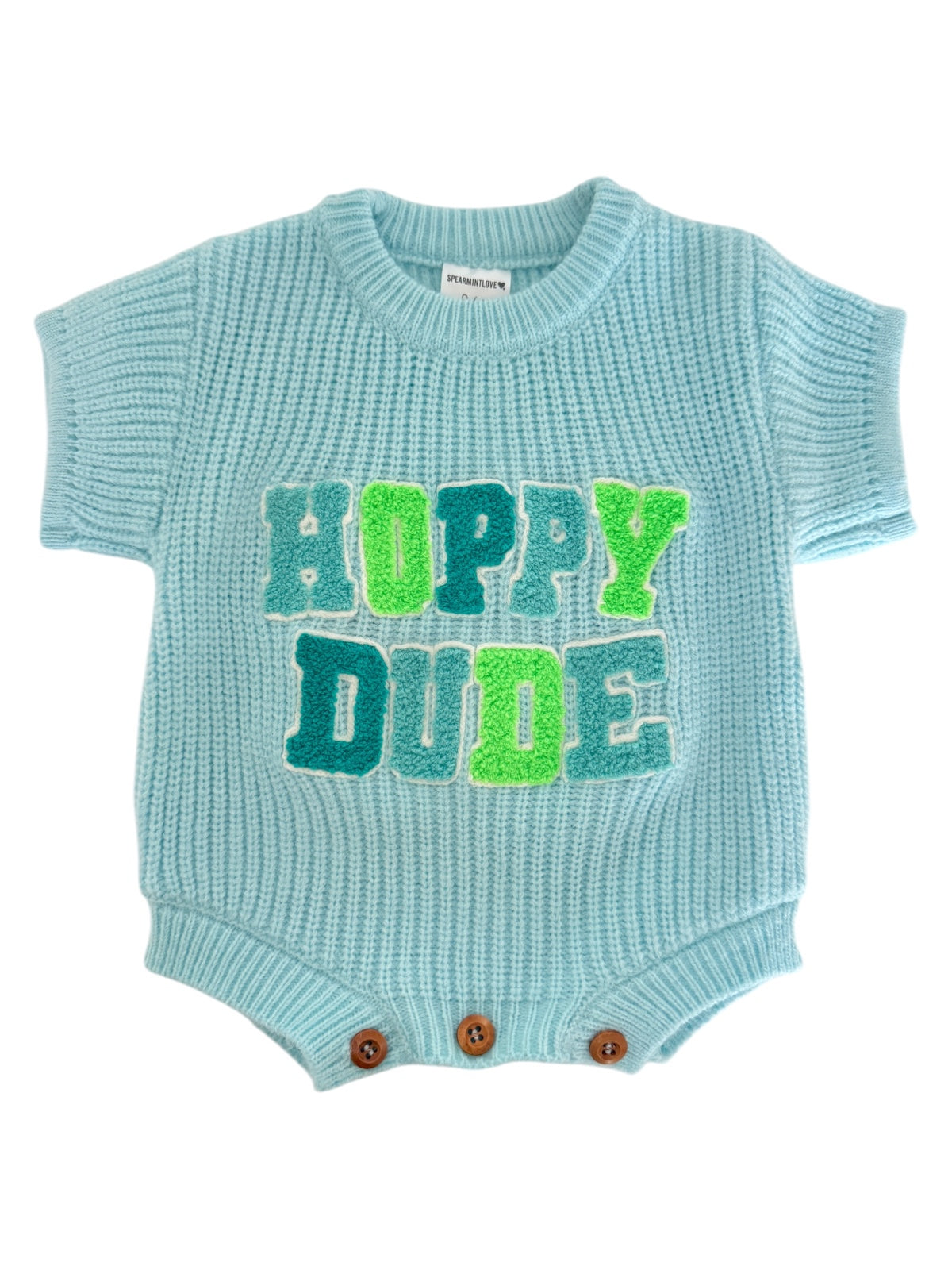 Light blue knitted baby romper with "Hoppy Dude" in bold green and blue letters. Features button closures.