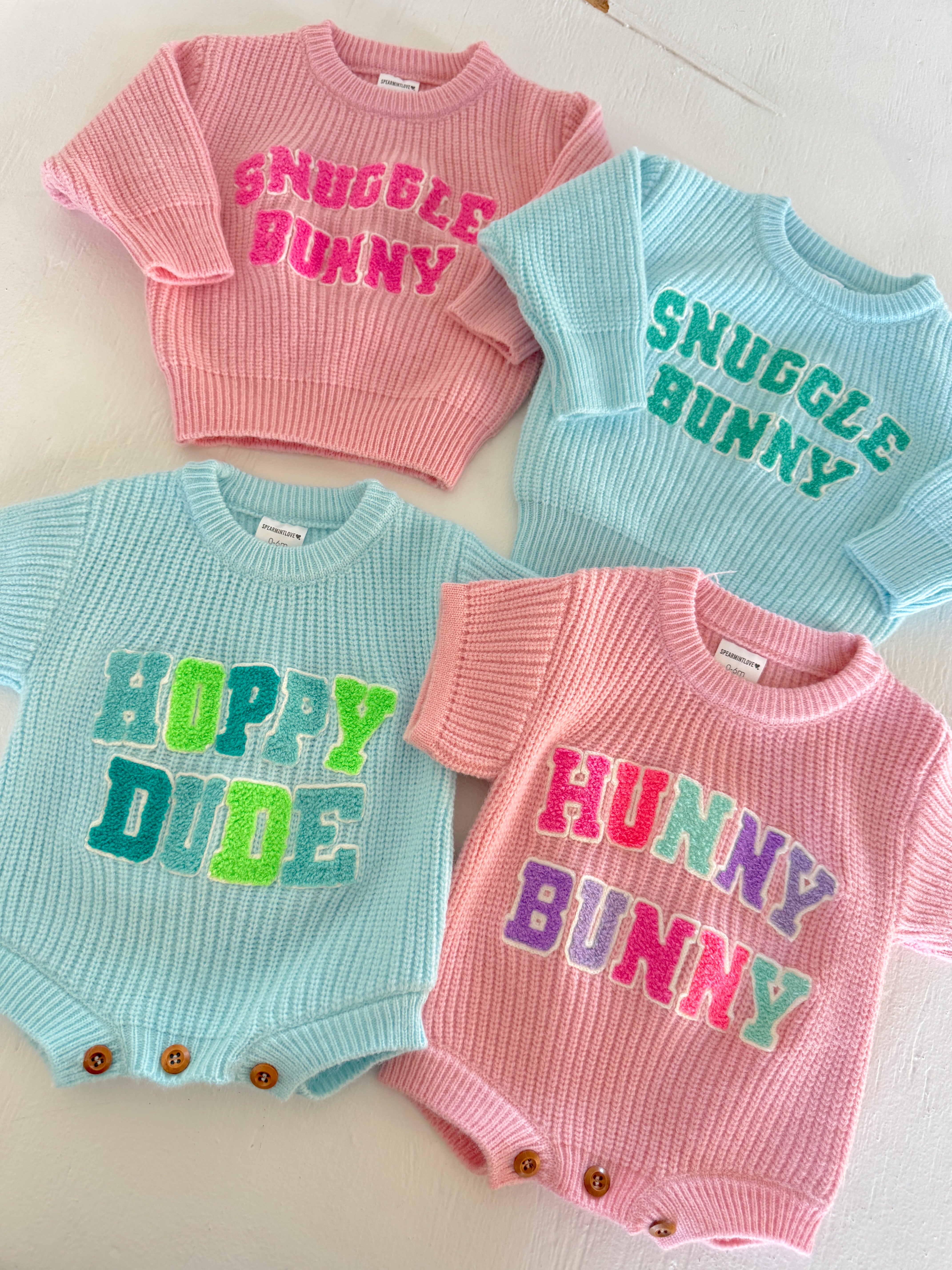 Four colorful children’s sweaters with playful text: "Snuggle Bunny", "Hoppy Dude", and "Hunny Bunny".