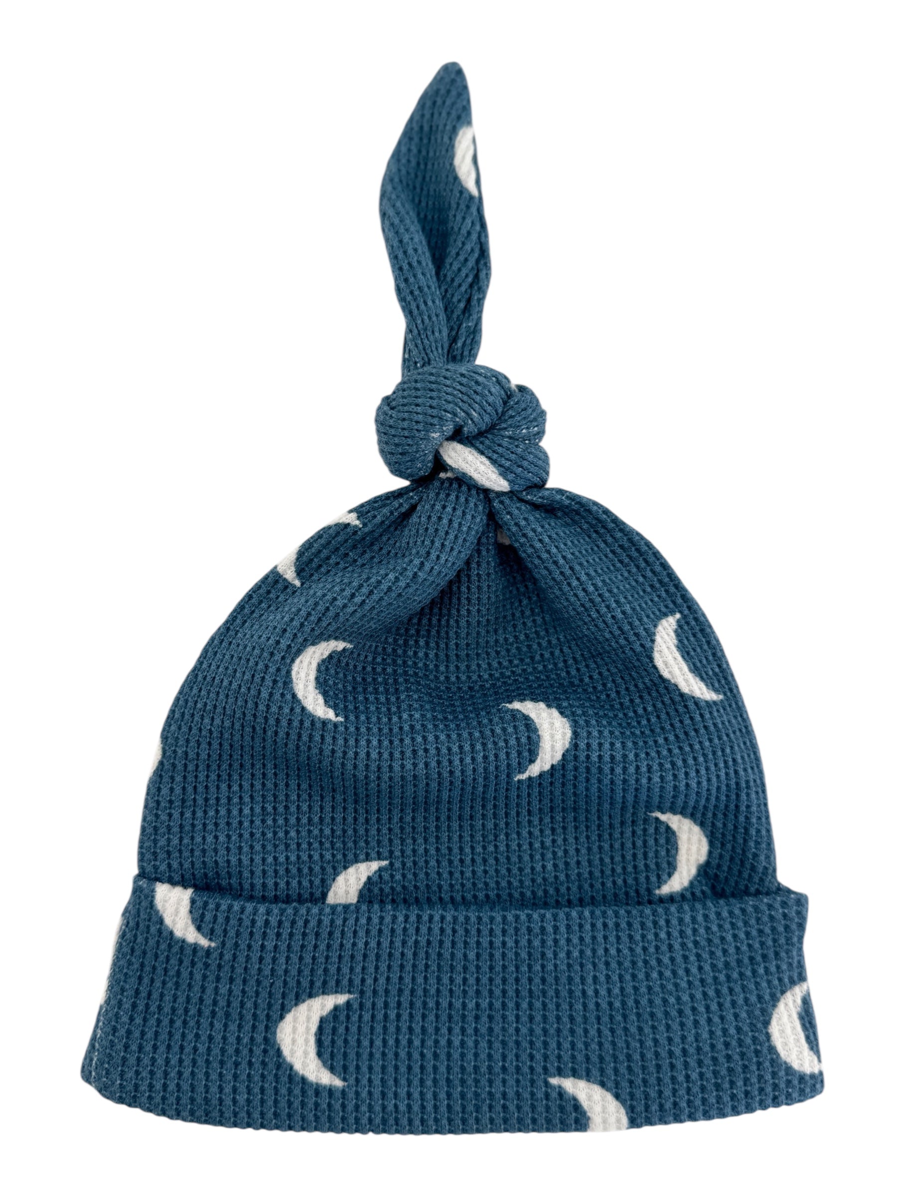 Blue knit hat with crescent moon patterns and a knotted top, suitable for infants.