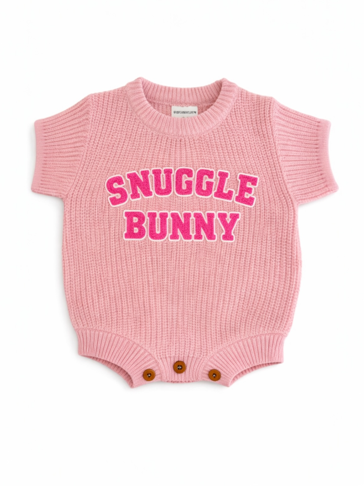 Pink ribbed baby onesie with "Snuggle Bunny" in bold pink letters and wooden button closures at the bottom.