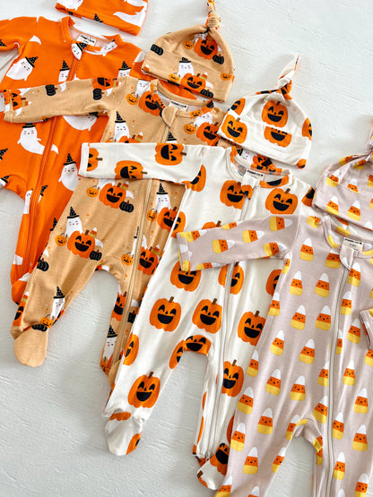 Assorted Halloween-themed baby outfits and hats in pumpkin and ghost designs arranged neatly on a white surface.