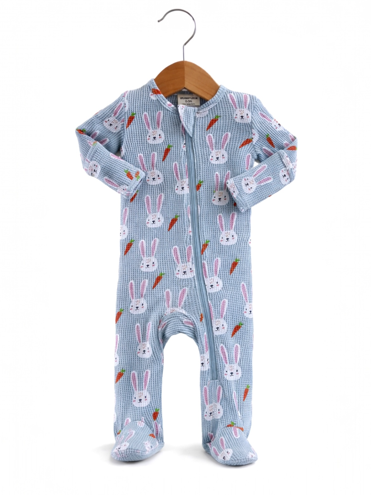 Baby blue onesie with bunny and carrot pattern hanging on a wooden hanger.