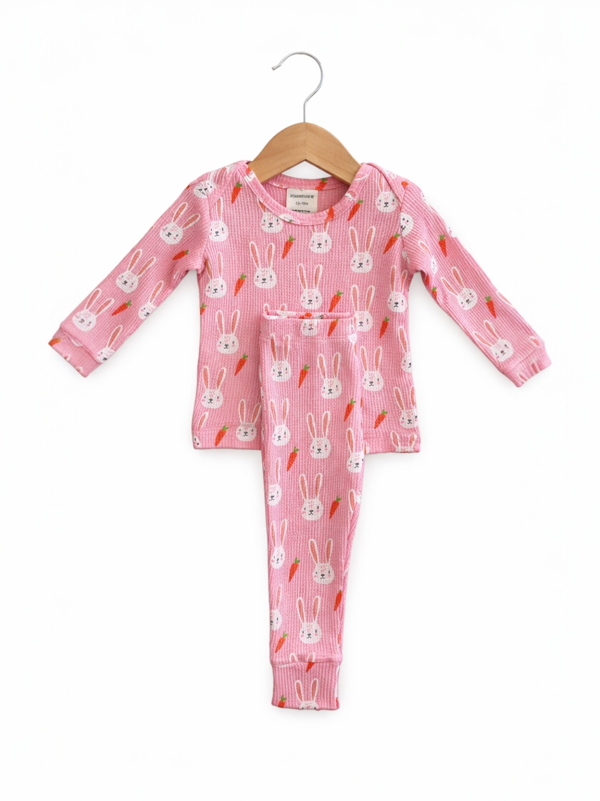 Pink children's pajama set with bunny and carrot patterns, featuring a long-sleeve top and matching pants.