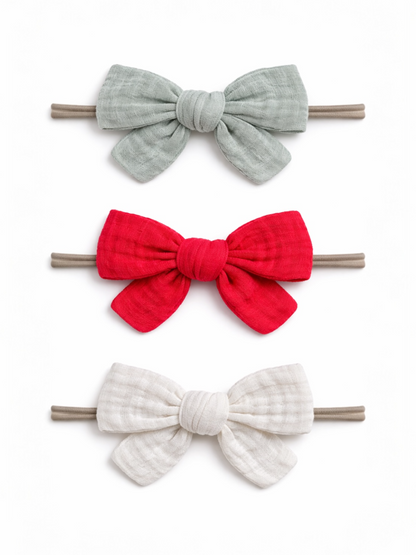 Three fabric hair bows in gray, red, and white on elastic bands, arranged vertically against a white background.