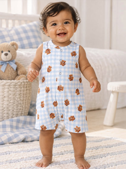 Smiling toddler in a bear-printed onesie, standing on a soft rug with a toy bear in the background.