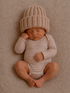 Newborn baby asleep on a soft blanket, wearing a striped onesie and a cozy knit hat.
