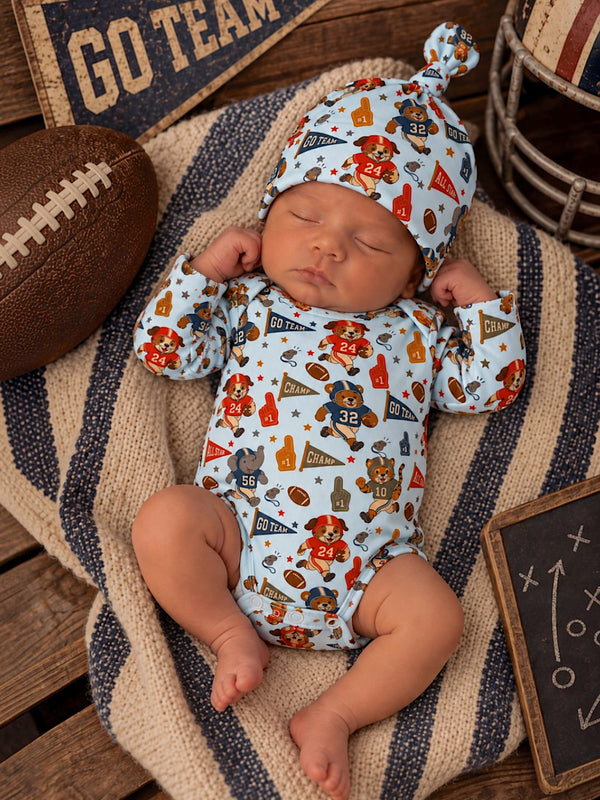 Baby boy sleeping on a blanket, wearing a colorful sports-themed onesie and matching hat, with a football nearby.