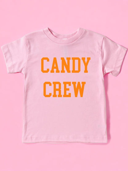 Pink t-shirt with orange text that reads "CANDY CREW." Background is solid pink.