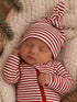 Sleeping baby in red and white striped outfit on a cozy blanket, with a tree branch in the background.