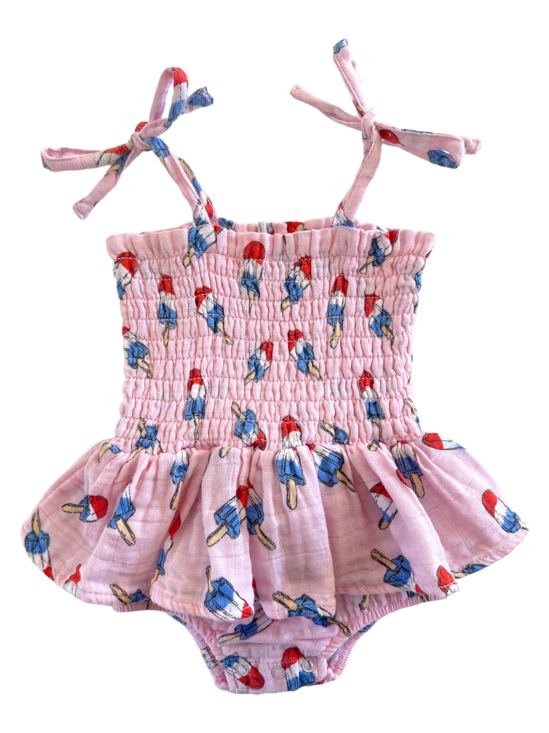 Pink toddler swimsuit with ice cream print and adjustable straps, featuring a smocked bodice and ruffled skirt.