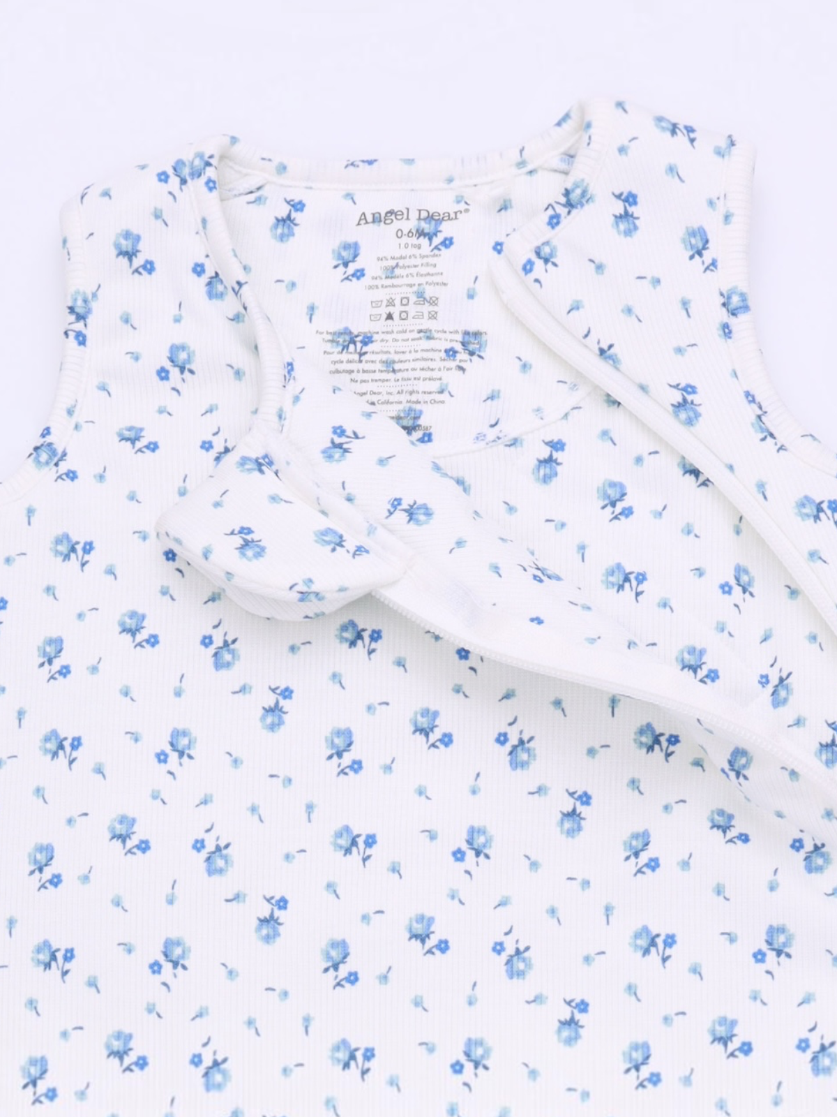 Floral-patterned baby outfit with soft fabric and tag details, featuring blue flowers on a white background.
