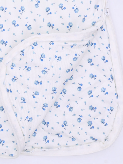 Floral patterned fabric with small blue flowers on a white background, partially folded over.