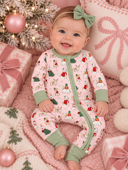 Smiling baby in festive pajamas, surrounded by holiday decorations and cozy pink textures.