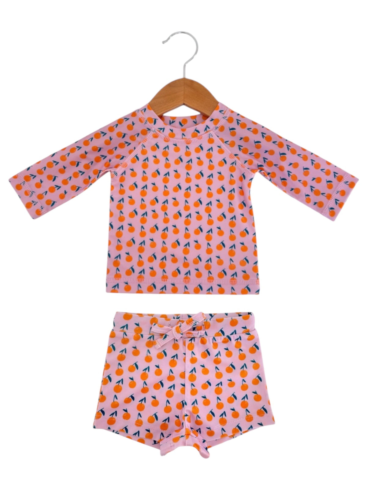 Kids' two-piece swim set featuring a long-sleeve top and shorts with colorful fruit pattern on pink background.