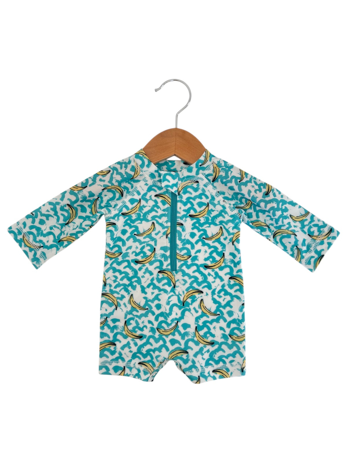 Children's swim romper with banana print, hanging on a wooden hanger against a white background.