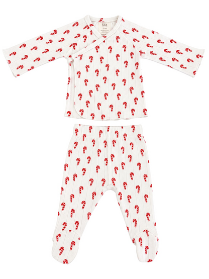 Baby pajama set featuring white fabric with red candy cane print, includes long-sleeve top and footed pants.