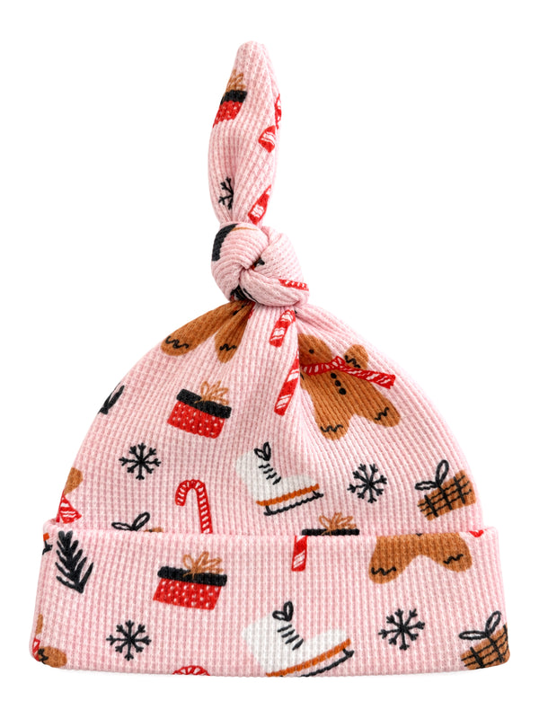 Pink knit baby hat with festive gingerbread, candy canes, and holiday patterns on a soft, stretchy fabric.