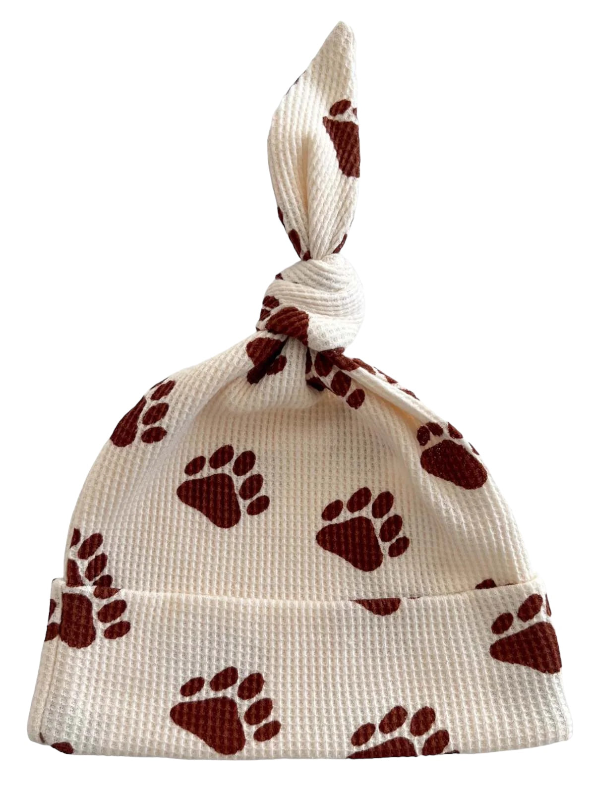 White baby hat with brown paw prints and a tied top. Ideal for stylish and cozy outfits.