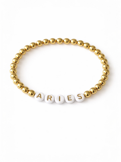 Gold and white beaded bracelet featuring the text "ARIES."